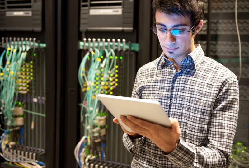 Man interacting with a tablet computer in a server room.