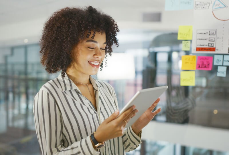 A female professional smiling while looking at a tablet