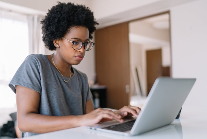 Woman wearing glasses interacting with a laptop.