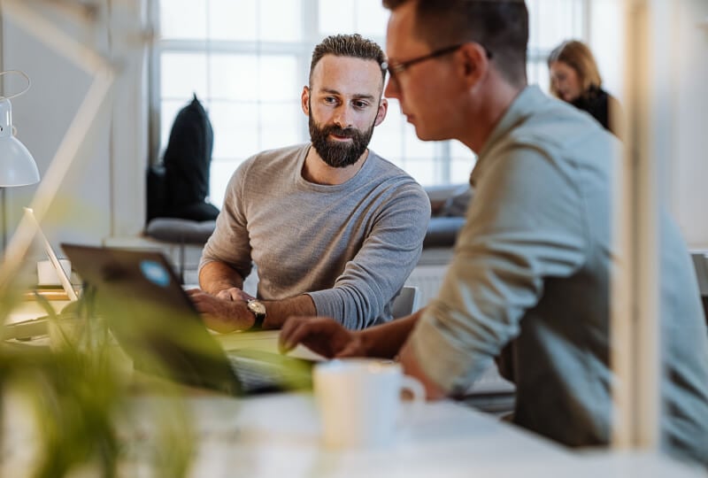 two men interacting with a laptop