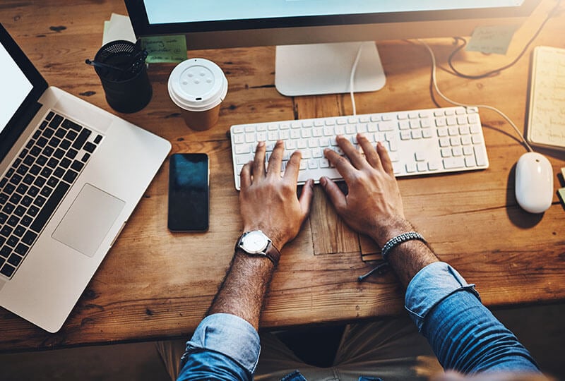 Overhead shot of a person's hands interacting with a keyboard.